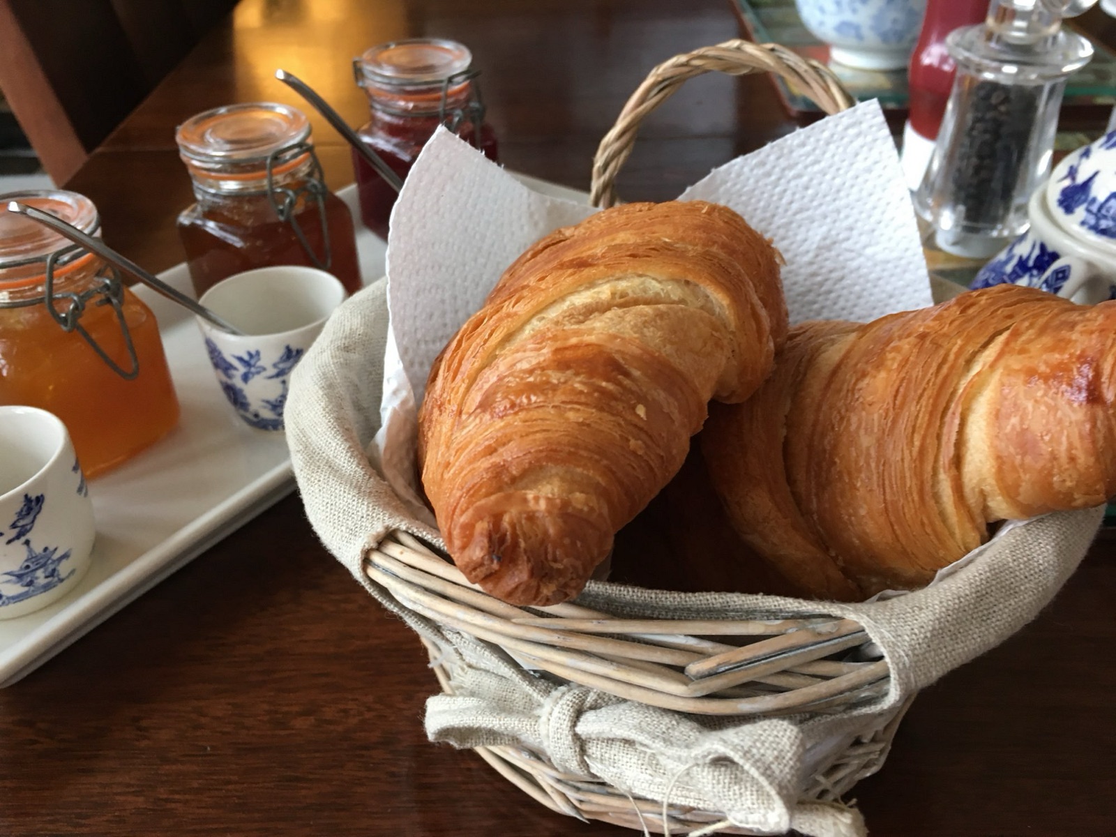 Croissants in a basket with jars of homemade jam and marmalade on the breakfast table