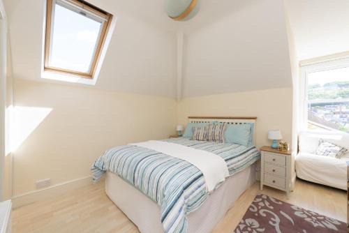 Attic double room with a skylight, striped bedding and a window onto the village